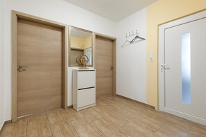 A hallway with wooden doors, a white cabinet with a mirror, and a coat rack.