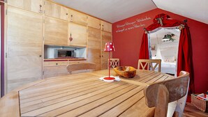 A dining area with a wooden table and chairs, a red wall with text, and a kitchen area with wooden cabinets. - 'Fantasy' Holiday Apartment with Wi-Fi (Lindau)