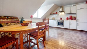 A kitchen with a wooden table and chairs, white cabinets, and a sloped ceiling. - 'Fantasy' Holiday Apartment with Wi-Fi (Lindau)
