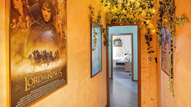 A corridor with a poster of 'The Lord of the Rings: The Fellowship of the Ring,' a bed, and ivy-covered walls. - 'Fantasy' Holiday Apartment with Wi-Fi (Lindau)