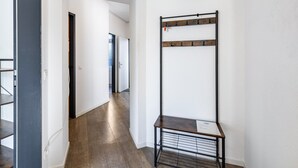 A hallway with a metal rack and a small table, wooden flooring, and white walls. - Bright Duisburg Apartment for Business Stays & Old Town (Duisburg)