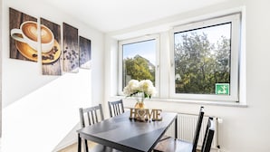A dining area with a table, chairs, a vase with flowers, and a 'HOME' sign. - Bright Duisburg Apartment for Business Stays & Old Town (Duisburg)