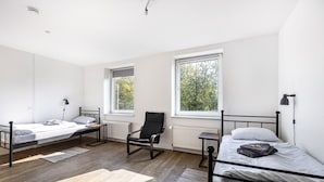 A room with three beds, a chair, and large windows. - Bright Duisburg Apartment for Business Stays & Old Town (Duisburg)