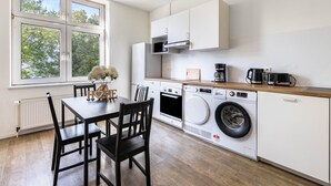 Una cocina moderna con una mesa de comedor, sillas, lavadora y cafetera.
