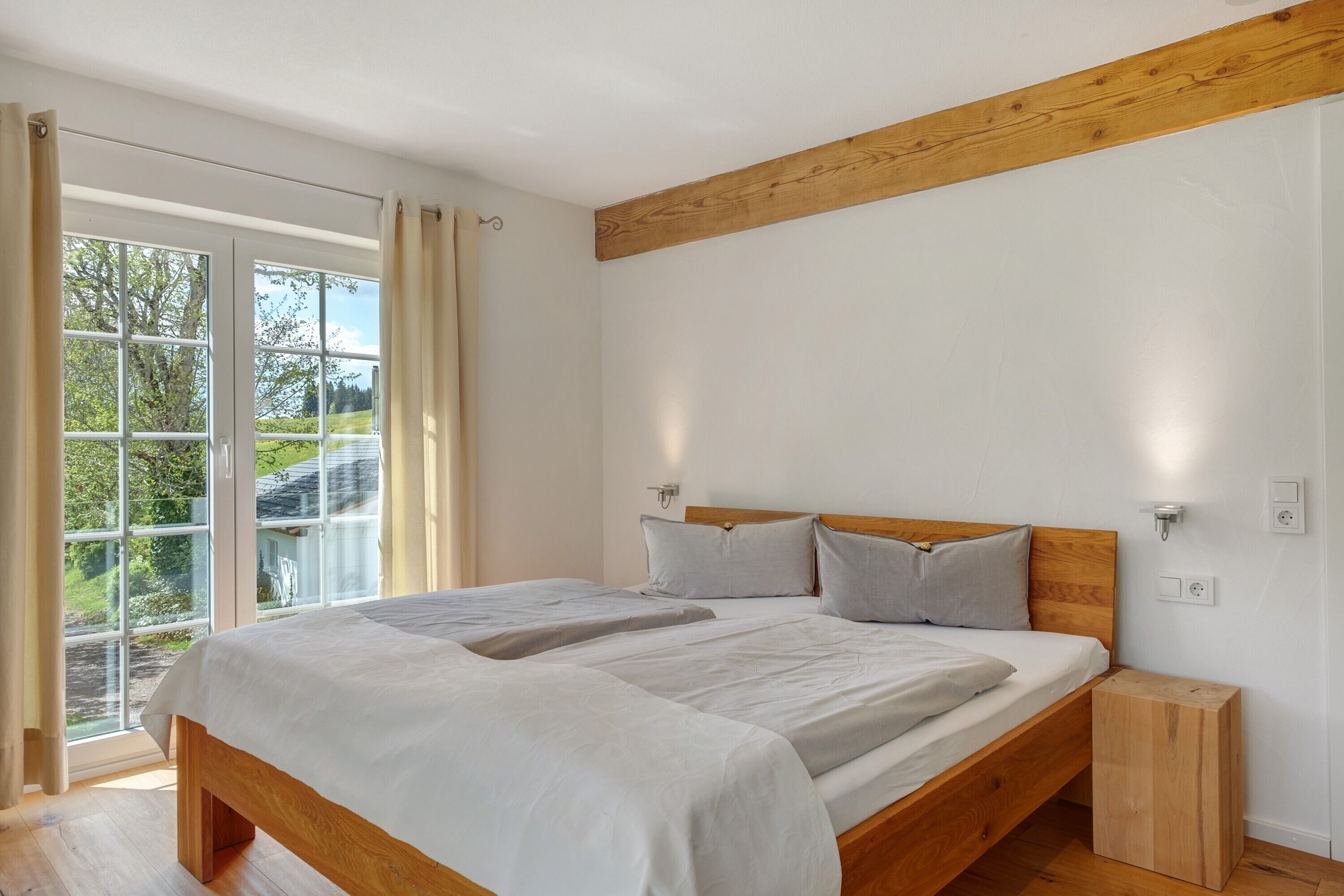 Een slaapkamer met een houten bed, een nachtkastje en een raam met gordijnen.