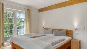 Een slaapkamer met een houten bed, een nachtkastje en een raam met gordijnen.