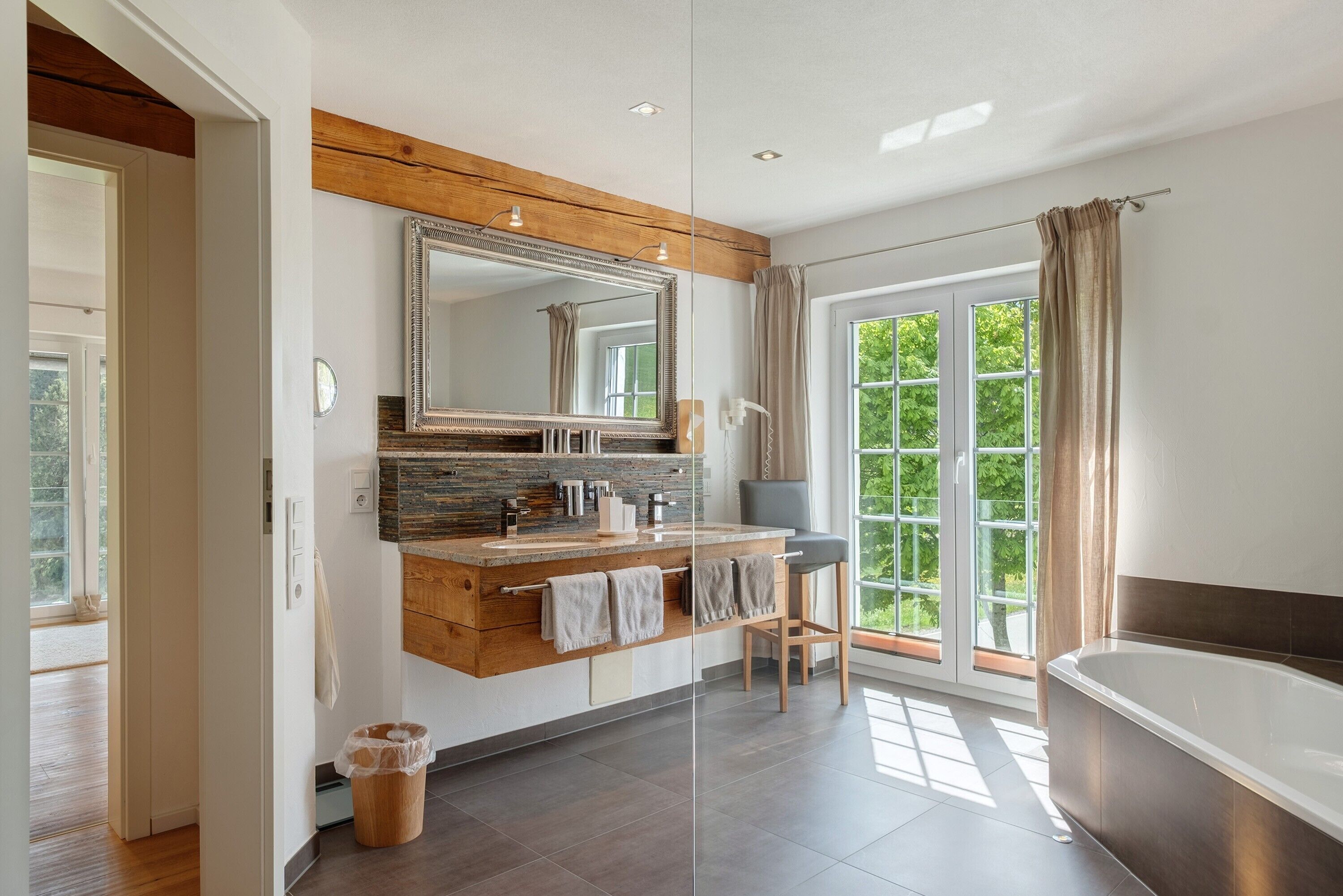 Een moderne badkamer met een grote spiegel, een houten wastafelmeubel en een bad.