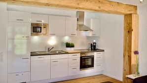 A modern kitchen with white cabinets, stainless steel appliances, and a wooden ceiling beam. - Apartment '2 Natursuite' with Valley View, Shared Garden, Sauna and Wi-Fi (Furtwangen im Schwarzwald)