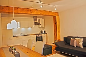 Eine moderne Küche mit weißen Schränken, Holzbalkendecke und Pendelleuchten.