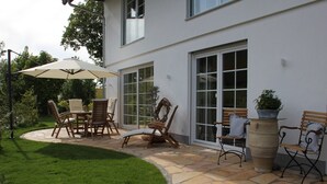 A patio with outdoor furniture, a large umbrella, and a potted plant.