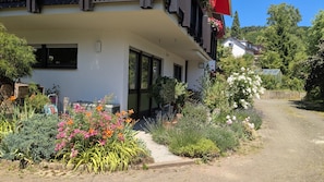 Un edificio con facciata bianca, ampie finestre e un balcone con ringhiere rosse.