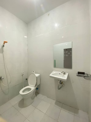 A small, clean bathroom with white tiles, a toilet, a sink, and a shower. - The Moonvine on 360 (Phnom Penh)