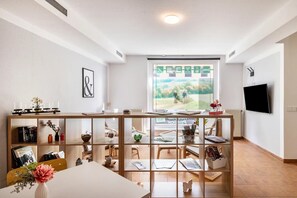 Un salon moderne doté d’une grande fenêtre, d’un téléviseur à écran plat et d’une bibliothèque en bois.