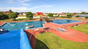 Una piscina con tobogán, un puente y una pista de atletismo roja.