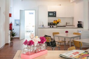 A modern kitchen with a microwave, a dining area with chairs, and a table with a vase of flowers.