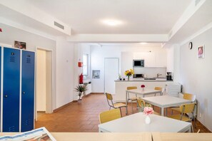 A hotel room with a dining area, kitchenette, and blue lockers.