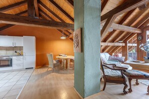 Une cuisine spacieuse équipée d’appareils électroménagers modernes, un coin repas avec une table et des chaises en bois, et un coin salon confortable avec un canapé et des fauteuils.