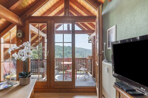 Une pièce aux murs en bois, dotée d’une porte-fenêtre coulissante qui donne sur un patio extérieur aménagé avec une table et des chaises.
