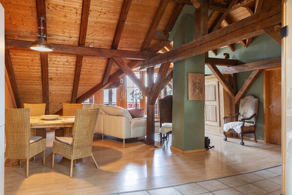Un espace repas doté d’un plafond en bois, de chaises en osier, d’une table et d’un canapé.