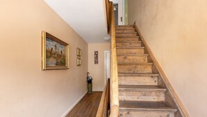 A wooden staircase with a handrail, beige walls, and a framed painting.