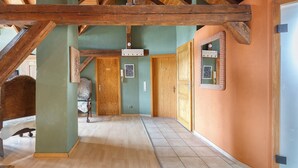 A hallway with wooden beams, a green wall, and a wooden door.