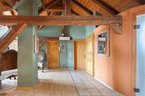 A hallway with wooden beams, a green wall, and a wooden door.