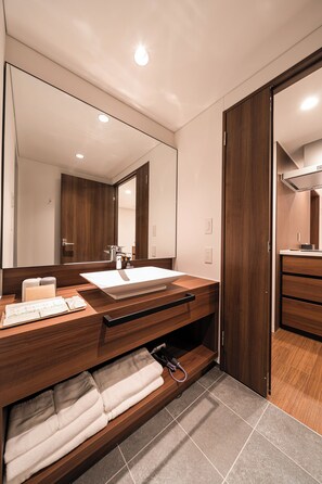A modern bathroom with a large mirror, wooden vanity, and a built-in towel rack. - Cava House (Tokyo)
