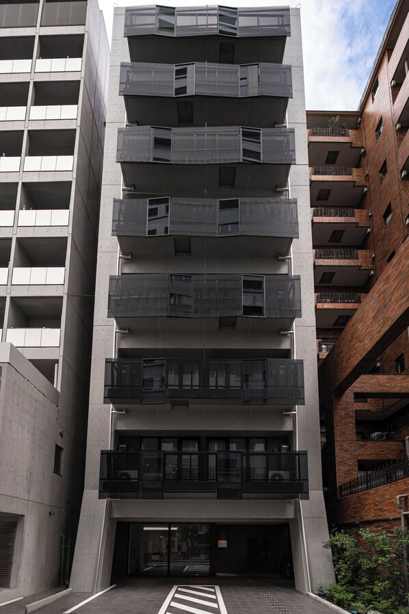 A multi-story building with balconies and a central entrance. - Cava House (Tokyo)