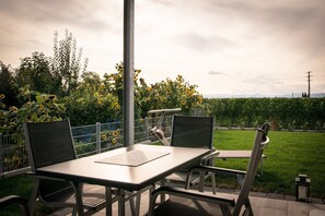 An outdoor patio with a table and chairs, surrounded by a garden with sunflowers and a hedge. - Apartment 'Südgarten' with Vineyard View, Private Terrace and Wi-Fi (Vogtsburg im Kaiserstuhl)