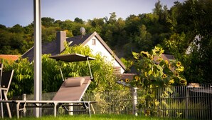 A house with a sloped roof, a satellite dish, and a fenced garden with sunflowers. - Apartment 'Südgarten' with Vineyard View, Private Terrace and Wi-Fi (Vogtsburg im Kaiserstuhl)