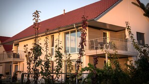 A two-story house with a red-tiled roof, large windows, and a balcony. - Apartment 'Südgarten' with Vineyard View, Private Terrace and Wi-Fi (Vogtsburg im Kaiserstuhl)