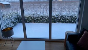 Een kamer met een groot raam, een witte tafel, een blauwe bank en een vloerlamp.