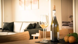 Een fles wijn en een glas op een tafel in een kamer met een bank en een bed op de achtergrond.