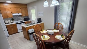 Une cuisine compacte avec des meubles en bois, une table à manger pour quatre personnes et un panneau indiquant l’emplacement du coin café.
