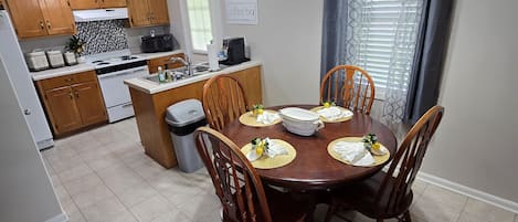 Une cuisine compacte avec des meubles en bois, une table à manger pour quatre personnes et un panneau indiquant l’emplacement du coin café.