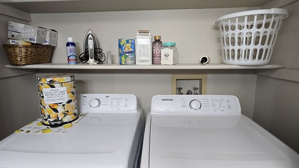 Un espace dédié à la lessive, comprenant deux machines à laver à chargement frontal, un panier et divers produits de lessive rangés sur des étagères.