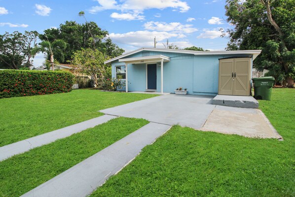 Una casa residencial con fachada azul, un porche delantero y un garaje.