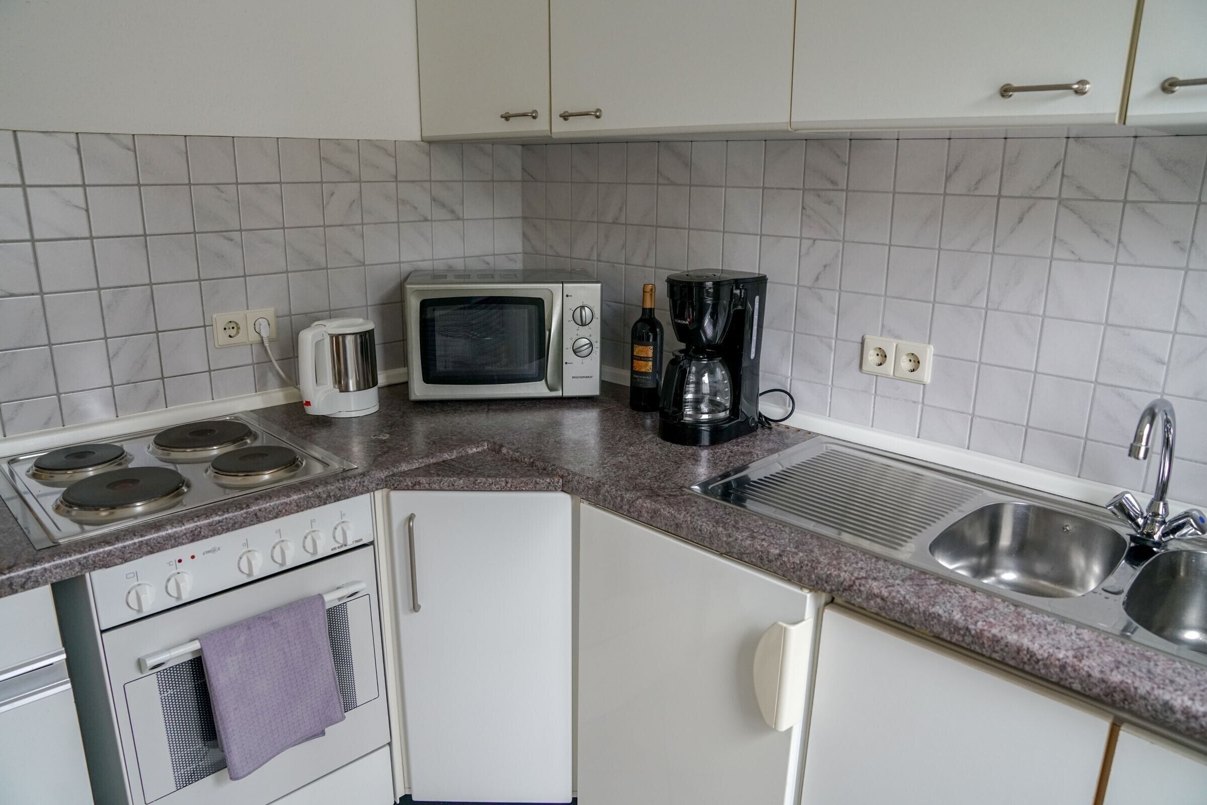 Una cocina equipada con microondas, cafetera y estufa.