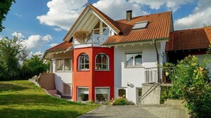 A two-story house with a red and white facade, a tiled roof, and a small balcony. - Apartment 'Roth' with Terrace and Wi-Fi (Frickingen)