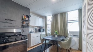 Une cuisine moderne équipée d’une cuisinière, d’un four à micro-ondes et de placards. On y trouve une table à manger avec des chaises, et une plante qui la décore.
