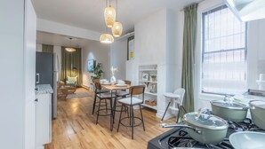 Une cuisine moderne avec un plancher en bois, un coin repas avec une table et des chaises, et une cuisinière avec des casseroles.