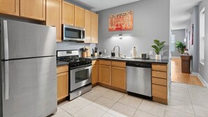 A modern kitchen with stainless steel appliances, wooden cabinets, and a tiled floor. - Charming 3-bedroom house in wonderful St. Louis with AC, WiFi (St. Louis)