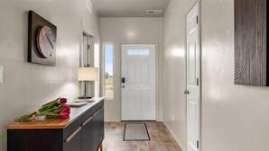 A hallway with a wooden floor, a desk with a lamp, a door at the end, and a wall-mounted clock. - Private 7-Acre Wine Trail Estate near Lake Lowell (Caldwell)