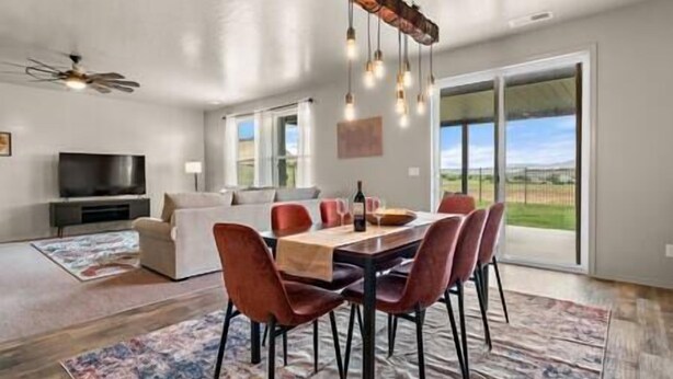 A spacious living room with a large TV, a dining area with a wooden table and red chairs, and a view of the outdoors through large sliding doors. - Private 7-Acre Wine Trail Estate near Lake Lowell (Caldwell)