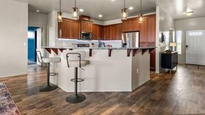 A modern kitchen with wooden cabinets, a central island with bar stools, stainless steel appliances, and pendant lighting. - Private 7-Acre Wine Trail Estate near Lake Lowell (Caldwell)