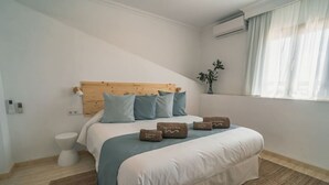 A bedroom with a wooden headboard, a bed with blue and white bedding, a bedside table, a white toilet, and a window with curtains. - Can Cama Rotja, pool, barbecue & incredible views (Inca)