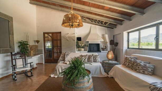 A cozy living room with a fireplace, a large window, and rustic decor. - Can Cama Rotja, pool, barbecue & incredible views (Inca)