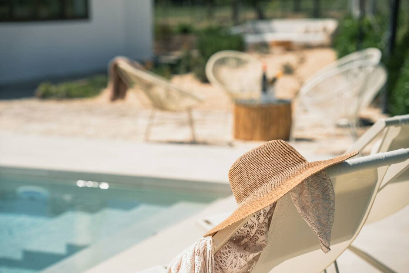 A poolside area with lounge chairs and a wooden table.