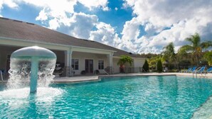 Una piscina con una fuente, un porche cubierto y un edificio con techo inclinado.
