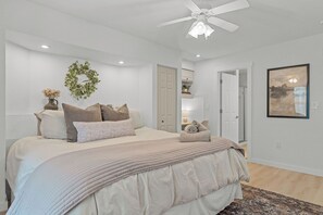 A bedroom with a bed, a ceiling fan, a door, and a wall-mounted artwork. - Gated Lake View Condo W/ pool, private boat ramp, putt putt, views of lake (Kimberling City)